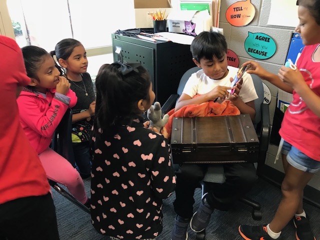 Students sharing items from a traveling suitcase