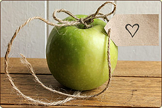 green apple with brown twine and a heart note tied to it